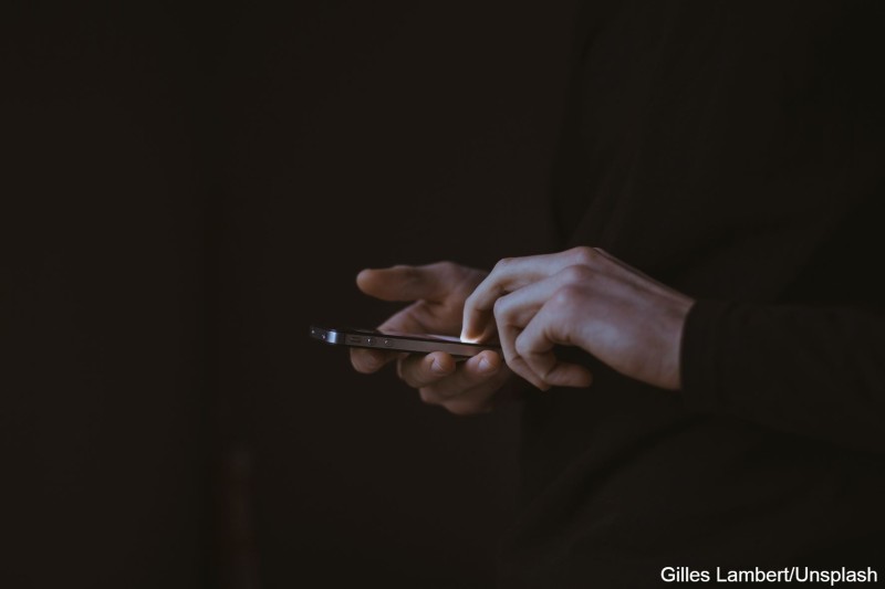 Ein dunkel gekleideter Mann benutzt ein Smartphone.