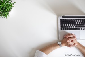 Mann sitzt vor seinem Laptop und wartet